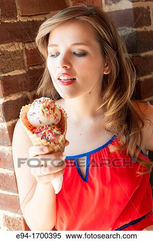 Stock Photography - Portrait of a 22 year old brunette woman outdoors with an ice cream cone. Fotosearch