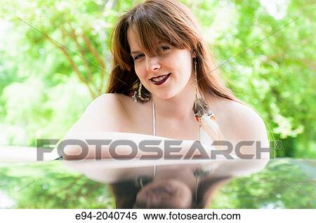 Portrait of a 22 year old brunette woman looking at the camera with face reflected in glass from below outdoors. View Large Photo Image Stock Photography - Portrait of a 22 year old brunette woman looking at the camera with face reflected in glass from below outdoors.. Fotosearch