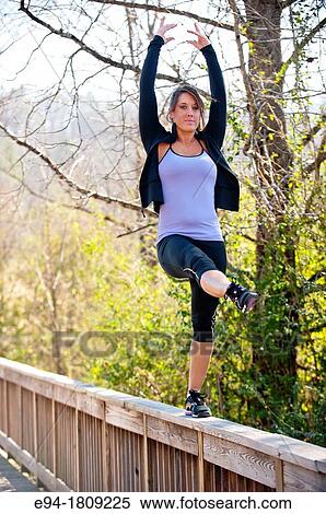 Portrait of a 23 year old brunette woman in workout clothing outdoors balancing on a fence View Large Photo Image Stock Photography - Portrait of a 23 year old brunette woman in workout clothing outdoors balancing on a fence. Fotosearch