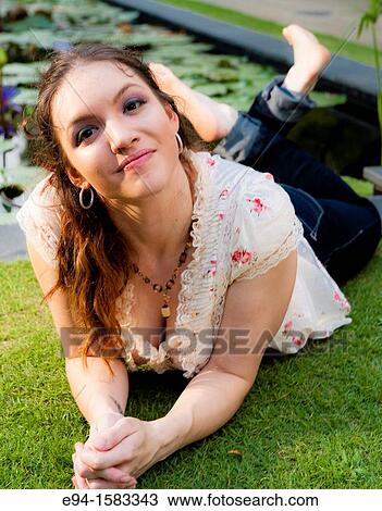 Portrait of a 24 year old brunette woman lying on her stomach on grass looking up at the camera View Large Photo Image Stock Image - Portrait of a 24 year old brunette woman lying on her stomach on grass looking up at the camera. Fotosearch