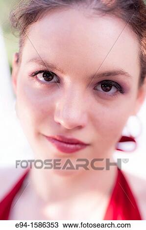 Stock Image - Portrait of a 24 year old brunette woman in a red dress near trees. Fotosearch