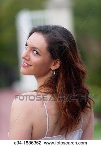 Portrait of a 24 year old brunette woman in a white dress in a garden looking over her shoulder View Large Photo Image Stock Image - Portrait of a 24 year old brunette woman in a white dress in a garden looking over her shoulder. Fotosearch
