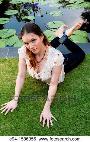 Portrait of a 24 year old brunette woman lying on her stomach on grass looking up at the camera View Large Photo Image Stock Photograph - Portrait of a 24 year old brunette woman lying on her stomach on grass looking up at the camera. Fotosearch