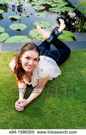 Portrait of a 24 year old brunette woman lying on her stomach on grass looking up at the camera View Large Photo Image Stock Photography - Portrait of a 24 year old brunette woman lying on her stomach on grass looking up at the camera. Fotosearch