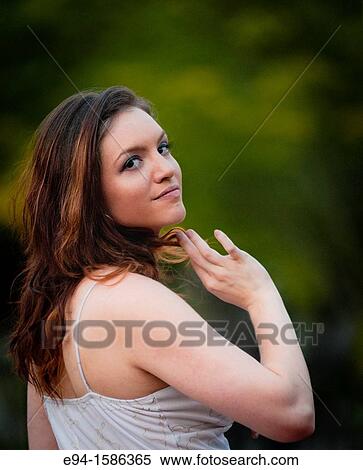 Portrait of a 24 year old brunette woman in a white dress in a garden looking over her shoulder View Large Photo Image Stock Photography - Portrait of a 24 year old brunette woman in a white dress in a garden looking over her shoulder. Fotosearch