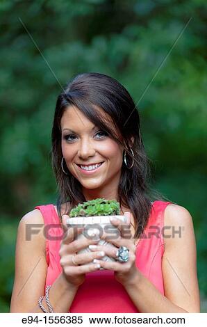 Portrait of a 25 year old brunette woman in a sleeveless dress in an outdoor garden setting holding a small Sempervivum, Hen & Chicks plant. View Large Photo Image Stock Photography - Portrait of a 25 year old brunette woman in a sleeveless dress in an outdoor garden setting holding a small Sempervivum, Hen & Chicks plant.. Fotosearch