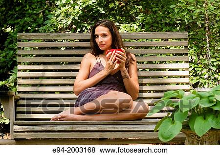 Portrait of a 27 year old brunette woman in a summer dress sitting on a bench looking at the camera in an outdoor setting holding a cup of coffee. View Large Photo Image Stock Photo - Portrait of a 27 year old brunette woman in a summer dress sitting on a bench looking at the camera in an outdoor setting holding a cup of coffee.. Fotosearch