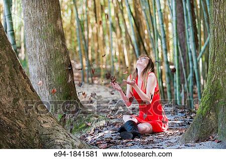 Stock Image - Portrait of a 30 year old redheaded woman outdoors playing with leaves. Fotosearch