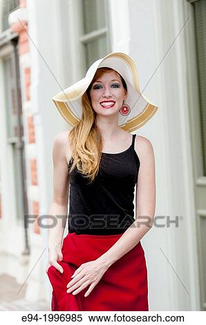Stock Photography - Portrait of a 31 year old red headed woman wearing a big hat in an urban setting.. Fotosearch