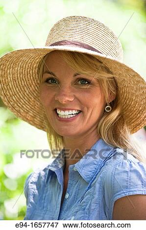 Portrait of a 35 year old blond woman wearing a straw hat and a blue blouse in a garden setting View Large Photo Image Stock Photo - Portrait of a 35 year old blond woman wearing a straw hat and a blue blouse in a garden setting. Fotosearch