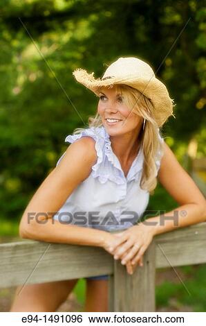 Portrait of a 35 year old blond woman with a straw hat leaning over a wooden rail fence in a country setting. View Large Photo Image Stock Photograph - Portrait of a 35 year old blond woman with a straw hat leaning over a wooden rail fence in a country setting.. Fotosearch
