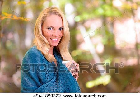 Portrait of a 38 year old blond woman wearing a sweater and holding a coffee cup looking at the camera in a forest setting in the fall View Large Photo Image Stock Image - Portrait of a 38 year old blond woman wearing a sweater and holding a coffee cup looking at the camera in a forest setting in the fall. Fotosearch