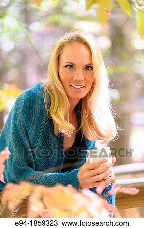 Portrait of a 38 year old blond woman wearing a sweater and holding a coffee cup looking at the camera in a forest setting in the fall View Large Photo Image Stock Image - Portrait of a 38 year old blond woman wearing a sweater and holding a coffee cup looking at the camera in a forest setting in the fall. Fotosearch