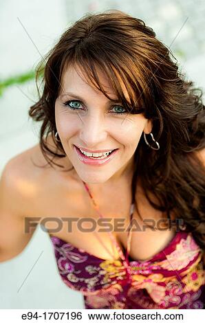 Stock Photograph - Portrait of a 39 year old brunette woman in casual clothing in a garden setting. Fotosearch