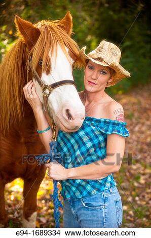 Portrait of a 41 year old blond woman wearing blue jeans walking with a horse in a country setting View Large Photo Image Picture - Portrait of a 41 year old blond woman wearing blue jeans walking with a horse in a country setting. Fotosearch