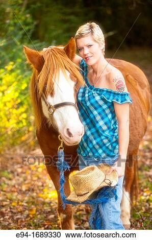 Portrait of a 41 year old blond woman wearing blue jeans walking with a horse in a country setting View Large Photo Image Stock Image - Portrait of a 41 year old blond woman wearing blue jeans walking with a horse in a country setting. Fotosearch