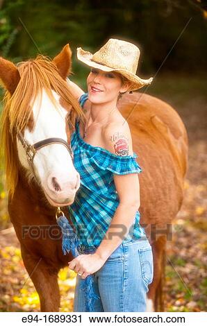 Portrait of a 41 year old blond woman wearing blue jeans walking with a horse in a country setting View Large Photo Image Stock Image - Portrait of a 41 year old blond woman wearing blue jeans walking with a horse in a country setting. Fotosearch