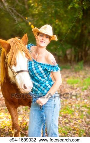 Portrait of a 41 year old blond woman wearing blue jeans walking with a horse in a country setting View Large Photo Image Stock Image - Portrait of a 41 year old blond woman wearing blue jeans walking with a horse in a country setting. Fotosearch
