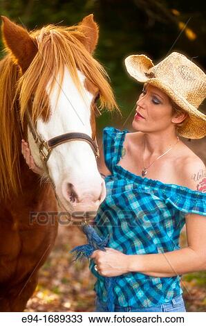 Portrait of a 41 year old blond woman wearing blue jeans walking with a horse in a country setting View Large Photo Image Stock Image - Portrait of a 41 year old blond woman wearing blue jeans walking with a horse in a country setting. Fotosearch