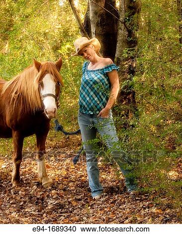 Portrait of a 41 year old blond woman wearing blue jeans walking with a horse in a country setting View Large Photo Image Stock Image - Portrait of a 41 year old blond woman wearing blue jeans walking with a horse in a country setting. Fotosearch