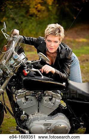 Portrait of a 41 year old blond woman looking at the camera leaning on a motorcycle View Large Photo Image Stock Image - Portrait of a 41 year old blond woman looking at the camera leaning on a motorcycle. Fotosearch
