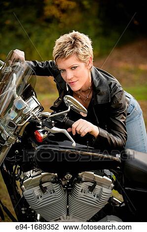 Portrait of a 41 year old blond woman looking at the camera leaning on a motorcycle View Large Photo Image Stock Image - Portrait of a 41 year old blond woman looking at the camera leaning on a motorcycle. Fotosearch
