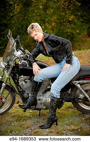 Portrait of a 41 year old blond woman looking at the camera sitting on a motorcycle View Large Photo Image Stock Image - Portrait of a 41 year old blond woman looking at the camera sitting on a motorcycle. Fotosearch
