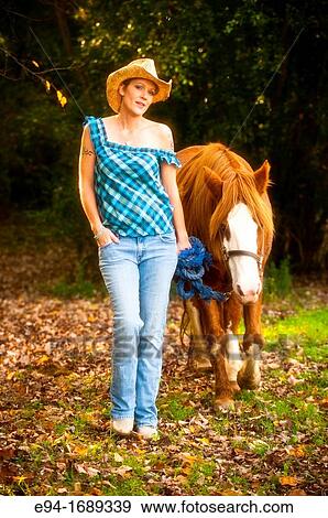 Portrait of a 41 year old blond woman wearing blue jeans walking with a horse in a country setting View Large Photo Image Stock Photo - Portrait of a 41 year old blond woman wearing blue jeans walking with a horse in a country setting. Fotosearch