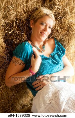 Portrait of a 41 year old blond woman looking at the camera reclining on hay bales in a barn View Large Photo Image Stock Photography - Portrait of a 41 year old blond woman looking at the camera reclining on hay bales in a barn. Fotosearch