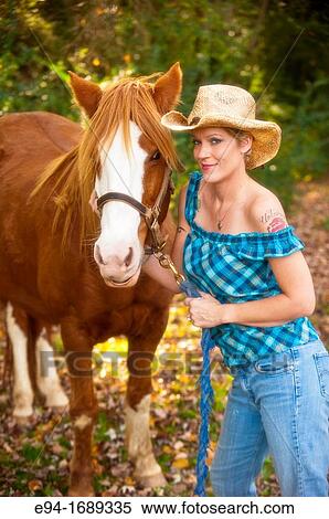 Portrait of a 41 year old blond woman wearing blue jeans walking with a horse in a country setting View Large Photo Image Stock Photography - Portrait of a 41 year old blond woman wearing blue jeans walking with a horse in a country setting. Fotosearch
