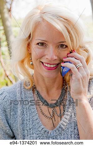 Portrait of a 44 year old blond woman talking on a mobile phone, outdoors View Large Photo Image Stock Image - Portrait of a 44 year old blond woman talking on a mobile phone, outdoors. Fotosearch