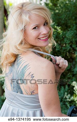 Portrait of a 44 year old blond woman, showing tatto on her back outdoors View Large Photo Image Stock Photography - Portrait of a 44 year old blond woman, showing tatto on her back outdoors. Fotosearch