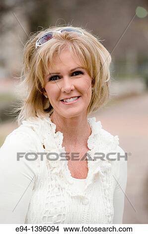 Portrait of a 50 year old blond woman in an outdoor setting smiling at the camera View Large Photo Image Picture - Portrait of a 50 year old blond woman in an outdoor setting smiling at the camera. Fotosearch