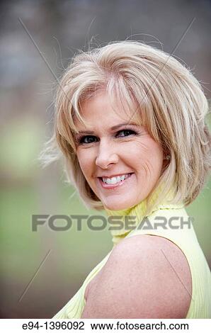 Portrait of a 50 year old blond woman in an outdoor setting smiling at the camera View Large Photo Image Stock Image - Portrait of a 50 year old blond woman in an outdoor setting smiling at the camera. Fotosearch
