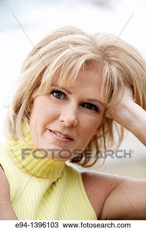 Stock Image - Portrait of a 50 year old blond woman in an outdoor setting smiling at the camera. Fotosearch