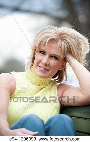 Stock Photo - Portrait of a 50 year old blond woman in an outdoor setting smiling at the camera. Fotosearch