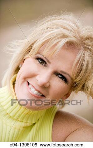 Stock Photography - Portrait of a 50 year old blond woman in an outdoor setting smiling at the camera. Fotosearch