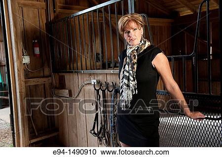 Portrait of a 52 year old blonde woman in casual black dress in a horse barn setting looking at the camera. View Large Photo Image Stock Image - Portrait of a 52 year old blonde woman in casual black dress in a horse barn setting looking at the camera.. Fotosearch