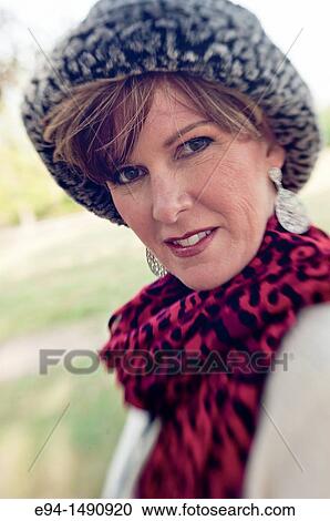 Portrait of a 52 year old blonde woman dressed in a white winter coat with a hat and a scarf in a country setting looking at the camera. View Large Photo Image Stock Image - Portrait of a 52 year old blonde woman dressed in a white winter coat with a hat and a scarf in a country setting looking at the camera.. Fotosearch