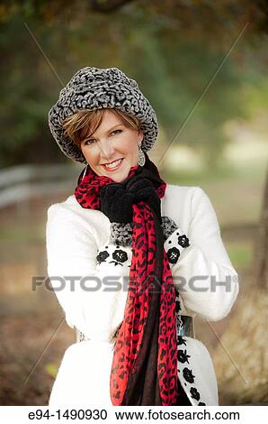 Portrait of a 52 year old blonde woman dressed in a white winter coat with a hat and a scarf in a country setting looking at the camera. View Large Photo Image Stock Image - Portrait of a 52 year old blonde woman dressed in a white winter coat with a hat and a scarf in a country setting looking at the camera.. Fotosearch