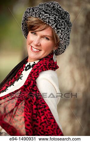 Portrait of a 52 year old blonde woman dressed in a white winter coat with a hat and a scarf in a country setting looking at the camera. View Large Photo Image Stock Image - Portrait of a 52 year old blonde woman dressed in a white winter coat with a hat and a scarf in a country setting looking at the camera.. Fotosearch