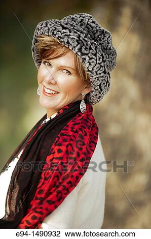 Portrait of a 52 year old blonde woman dressed in a white winter coat with a hat and a scarf in a country setting looking at the camera. View Large Photo Image Stock Image - Portrait of a 52 year old blonde woman dressed in a white winter coat with a hat and a scarf in a country setting looking at the camera.. Fotosearch