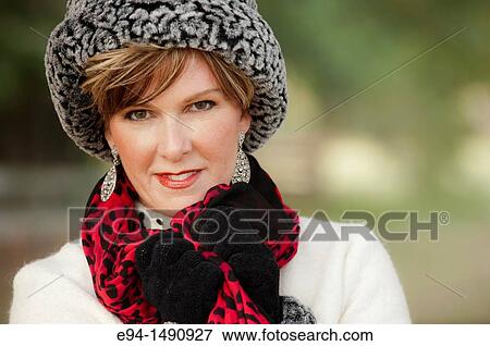 Portrait of a 52 year old blonde woman dressed in a white winter coat with a hat and a scarf in a country setting looking at the camera. View Large Photo Image Stock Photo - Portrait of a 52 year old blonde woman dressed in a white winter coat with a hat and a scarf in a country setting looking at the camera.. Fotosearch