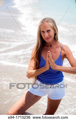 Portrait of a 57 year old woman on a beach smiling at the camera hands in prayer pose View Large Photo Image Stock Photograph - Portrait of a 57 year old woman on a beach smiling at the camera hands in prayer pose. Fotosearch