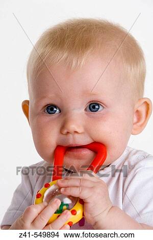 Picture - Portrait of a baby with a toy in her mouth.. Fotosearch