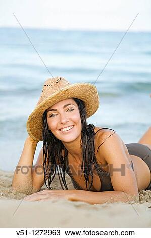 Portrait of a beautiful brunette woman smiling at camera with a hat at the beach View Large Photo Image Stock Image - Portrait of a beautiful brunette woman smiling at camera with a hat at the beach. Fotosearch