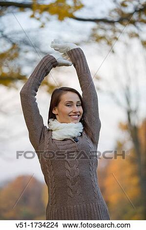 Picture - Portrait of a beautiful young woman stretching in the park in Autumn. Fotosearch