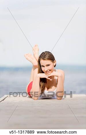 Portrait of a beautiful young woman lying down on a pier and smiling at camera View Large Photo Image Stock Photo - Portrait of a beautiful young woman lying down on a pier and smiling at camera. Fotosearch