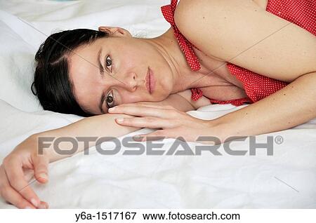 Portrait of a beautiful young woman lying on bed View Large Photo Image Stock Photo - Portrait of a beautiful young woman lying on bed. Fotosearch