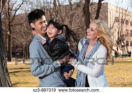 Stock Photo - Portrait of a bi-racial family having fun outdoors. Fotosearch